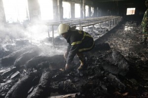 A firefighter inspects a garment factory after a devastating fire in Savar November 25, 2012. A fire swept through a garment factory on the outskirts of Bangladesh's capital killing more than 100 people, the fire brigade said on Sunday, in the country's worst ever factory blaze. REUTERS/Andrew Biraj (BANGLADESH - Tags: DISASTER BUSINESS TEXTILE)